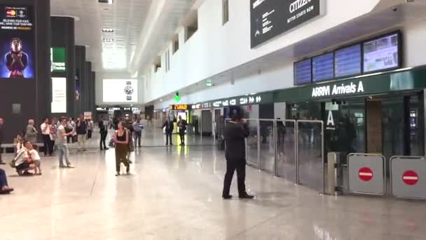 Personas a la espera de llegadas a la puerta de llegada en el aeropuerto de Malpensa — Vídeos de Stock