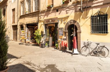Lucca, Toskana, İtalya - 3 Temmuz 2019: Eski tarihi şehir Lucca 'nın merkezinde bar ve dükkanları olan eski dar bir ortaçağ sokağı