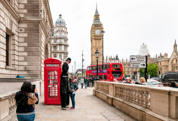 Street artist perform in front of a red phone booth — Stock Photo, Image