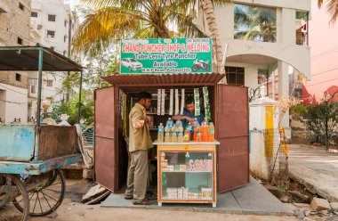 Puttaparthi, Andhra Pradesh, Hindistan - 11 Ocak 2013: Puttaparthi 'de bir satıcı ve bir alıcıyla içki, sigara ve küçük eşyalar satan küçük bir sokak dükkanı.