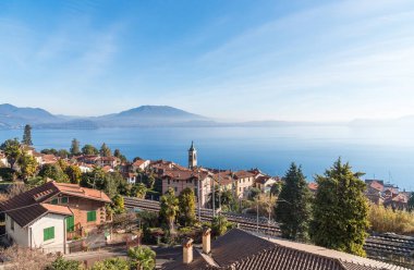 Dağları ve mavi suları olan Belgirate köyünden Maggiore Gölü 'nün panoramik manzarası, Piedmont, İtalya