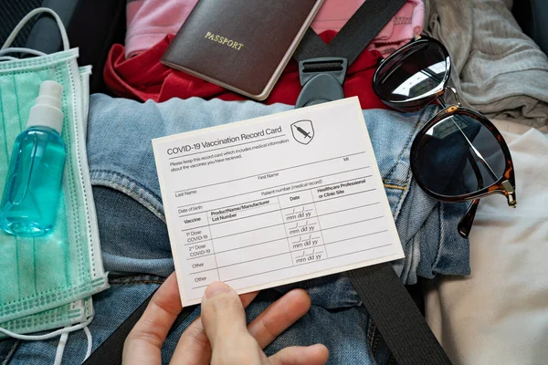 Salgın çağında bavul hazırlamak. Yüz maskesi, el dezenfektanı ve aşı pasaportuyla seyahat ediyor..