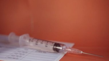 Bir aşı şişesi, eldivenli bir elle çerçeveye kayıyordu.