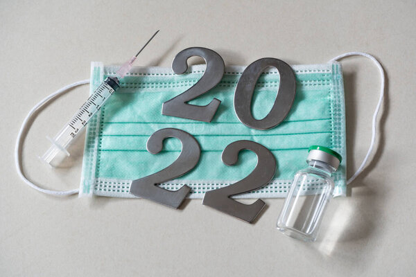 2022 with face mask, syringe and vaccine vial