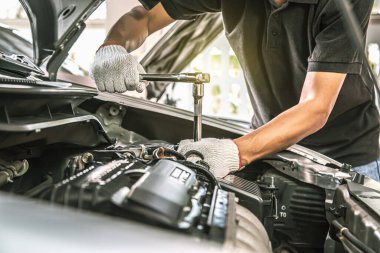 Otomobil tamircisinin yakın çekim elleri araba garajındaki bir araba motorunu tamir etmek için ingiliz anahtarını kullanıyor. Araba bakımı, tamirat ve hizmet kavramları.