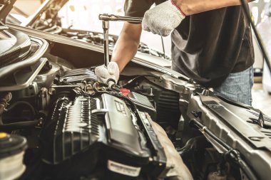 Otomobil tamircisinin yakın çekim elleri araba garajındaki bir araba motorunu tamir etmek için ingiliz anahtarını kullanıyor. Araba bakımı, tamirat ve hizmet kavramları.
