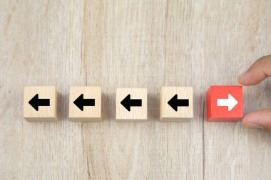 İş adamı eli, büyümedeki değişim ve başarı kavramlarının iş liderleri için zıt yönleri gösteren ok başlıklı tahta bloğu seçiyor..