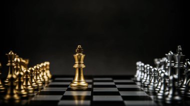 Satranç tahtasında gümüş satranç takımının karşısında duran Kral Altın Satranç. İş ekibi kavramı ve stratejik plan, lider ve risk yönetimi stratejisi.