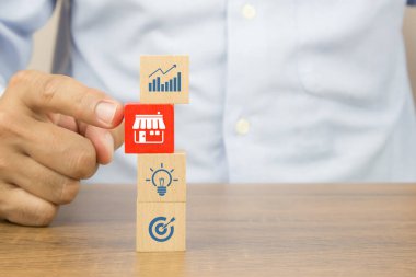 Yakından bakınca, içi bayilik mağazası ikonu dolu küp tahta oyuncak blokları seçiyor. Küçük işletmeler için finansal pazarlama planlamasının büyüme ve genişleme stratejisidir.
