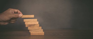 Yakın plan el, çöküşü veya finansal risk yönetimi ve stratejik planlama kavramlarını önlemek için tahta bloğu merdivenlere yığıyor..