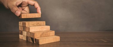 Yakın plan el, çöküşü veya finansal risk yönetimi ve stratejik planlama kavramlarını önlemek için tahta bloğu merdivenlere yığıyor..