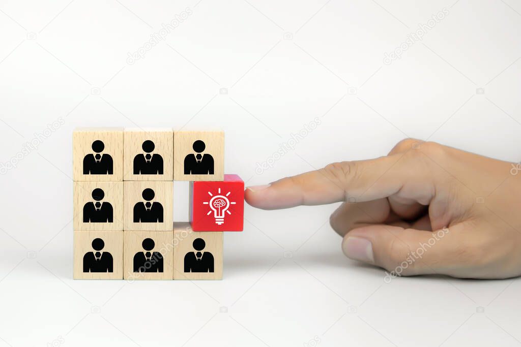 Close up hand choosing a light bulb on people icon on cube wooden toy blocks concepts of human resources for business team organizations and leadership.