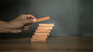 Yakın plan el, çöküşü veya finansal risk yönetimi ve stratejik planlama kavramlarını önlemek için tahta bloğu merdivenlere yığıyor..