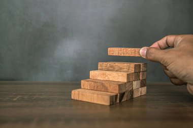 Yakın plan el, çöküşü veya finansal risk yönetimi ve stratejik planlama kavramlarını önlemek için tahta bloğu merdivenlere yığıyor..