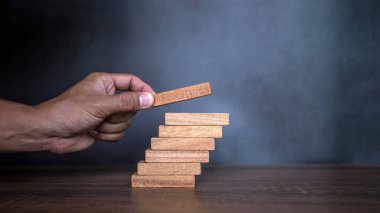 Yakın plan el, çöküşü veya finansal risk yönetimi ve stratejik planlama kavramlarını önlemek için tahta bloğu merdivenlere yığıyor..
