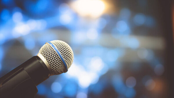 Public speaking backgrounds, Close-up the microphone on stand for speaker speech at seminar room with technology light background and blur bokeh.