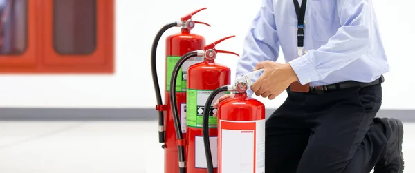 緊急時や安全救助や火災訓練のためのケースを防止するための建物の概念に赤い消火器タンクのハンドルをチェックオフィスの男 — ストック写真