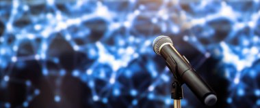 Toplum önünde konuşma geçmişi, seminer odasında konuşma yapmak için mikrofonu kapatın. Teknolojik ışık arka planı ve bulanık bokeh.