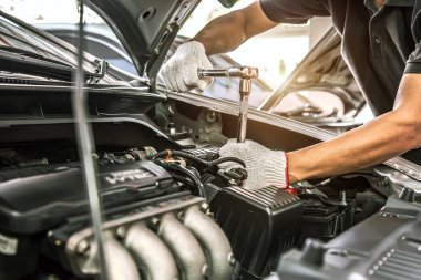 Otomobil tamircisinin yakın çekimli elleri araba tamirhanesinde tamir ve bakım için ingiliz anahtarını kullanıyor. Araç bakımı kontrolü ve sabit ve hizmet sigortası kavramları.