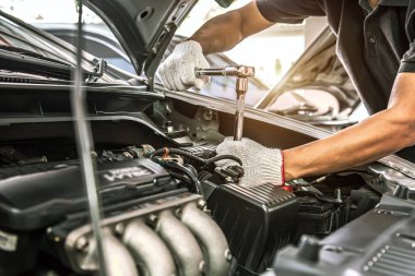 Close-up hands of auto mechanic are using the wrench to repair and maintenance auto engine is problems at car repair shop. Concepts of car care check and fixed and services insurance. clipart