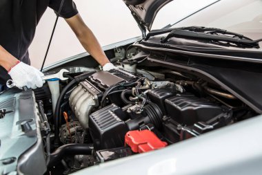 Otomobil tamircisinin yakın çekimli elleri araba tamirhanesinde tamir ve bakım için ingiliz anahtarını kullanıyor. Araç bakımı kontrolü ve sabit ve hizmet sigortası kavramları.