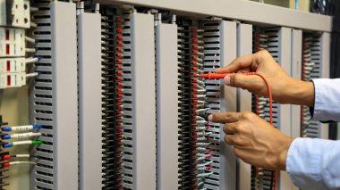 Elektrik mühendisinin ölçüm ekipmanlarını kullanarak devre kesici ve kablo tesisat sistemindeki elektrik akımını kontrol ederek ana güç dağıtım panosunun bakımı için yakın çekim eli..