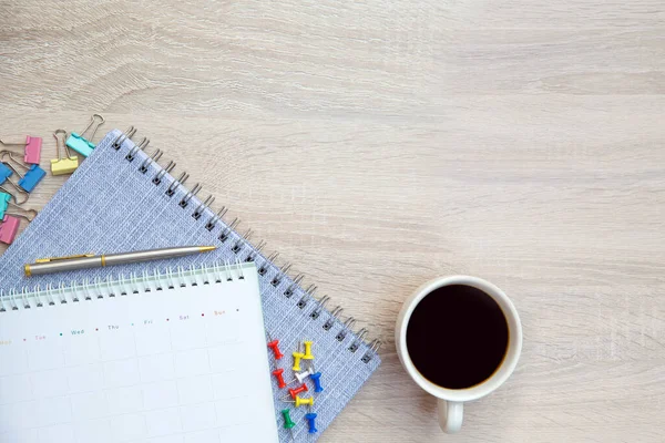 The top view desk and blank calendar with a pen and office equipment for working area copy space composition and work from home concepts.