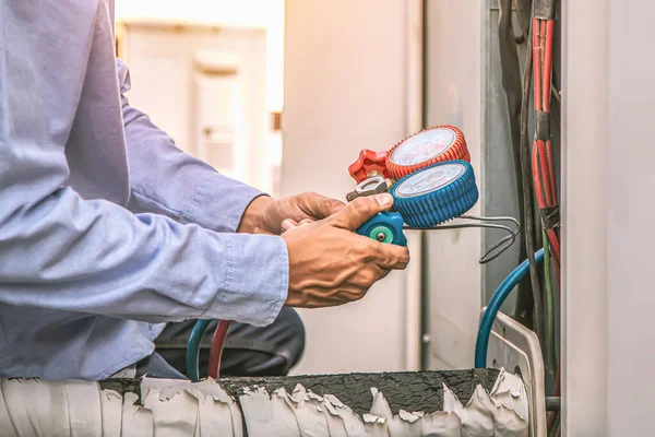 Açık hava kompresör ünitesini temizleyip kontrol ettikten sonra endüstriyel fabrika klimalarını doldurmak için ölçüm manifoldları kullanarak mühendisin elini kapat.