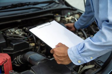 Otomobil tamircisi tamir edildikten sonra araç motoru sistemleri için kontrol listesi kullanıyor. Araba tamir ve onarım ve hizmet bakımı kavramları.