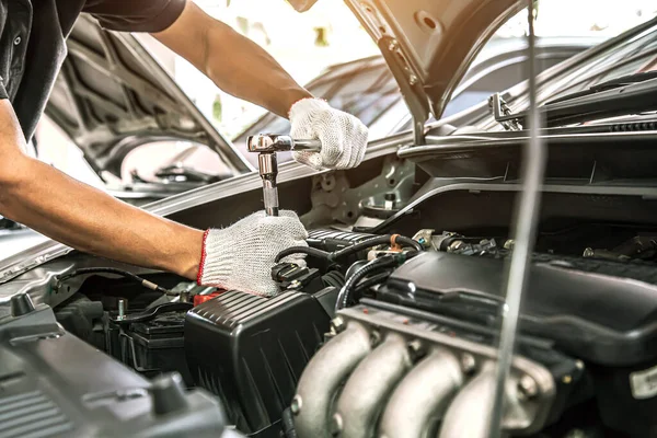 自動車整備士のクローズアップ手は 修理にレンチを使用しており メンテナンスの自動車エンジンは車の修理店での問題です 車のケアチェックと固定とサービスの概念保険 ストックフォト