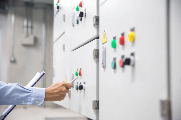 Electrical engineer checking electrical voltage at circuit breaker air handling unit (AHU) starter control panel for air conditioner load center cabinet for maintenance power system distribution.