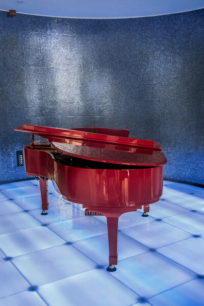 Red piano on blue club scene.