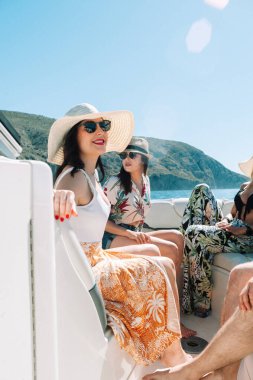 Yelkenli güvertesinde oturup eğlenen arkadaşlar. Tatil, seyahat, deniz, arkadaşlık ve insanlar kavramı.