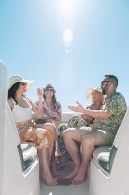 Yelkenli güvertesinde oturup eğlenen arkadaşlar. Tatil, seyahat, deniz, arkadaşlık ve insanlar kavramı.