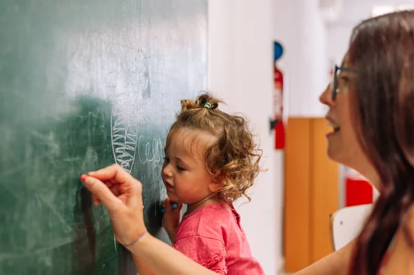Kindergarten Teacher Supports Child on Class