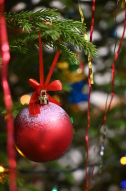 Süslü Noel ağacında asılı kırmızı kurdele yayı olan kırmızı top. Yakın plan..