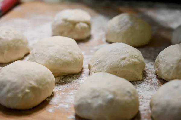 Raw dough balls and flour on wooden counter. Preparation for cooking pastries.