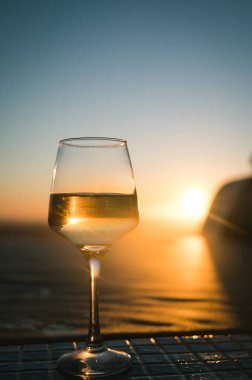 Şampanyalı şampanyayla yakın plan. Arkaplanda gün batımı gökyüzü.