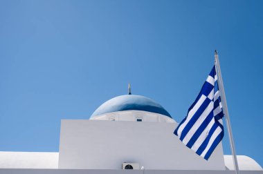 Yunanistan 'daki geleneksel Ortodoks kilisesinin alt manzarası. Mavi kubbeli beyaz bina. Yunan bayrağı.