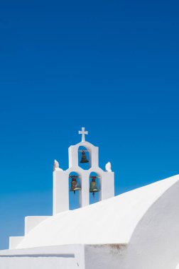 Santorini adasındaki geleneksel Rum Ortodoks kilisesinin beyaz çan kulesi. Arka planda mavi gökyüzü.