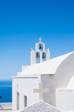 Santorini adasındaki geleneksel Rum Ortodoks kilisesinin beyaz çan kulesi. Arka planda mavi gökyüzü.