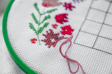 Çapraz dikişe yakın çekim. İpliği olan bir iğne tuvale sıkıştı. Bir parça nakış.