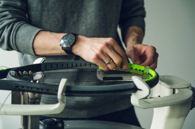 Close-up of tennis racket on electronic stringing machine. Process of replacement synthetic gut string before game. Hands of stringer. clipart