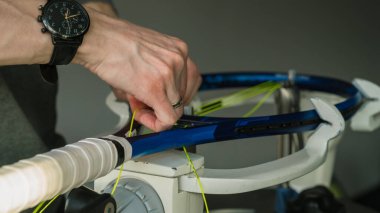 Elektronik telli makinede tenis raketinin yakın çekimi. Oyundan önce sentetik bağırsak teli değiştirme işlemi. Gazetecinin elleri.