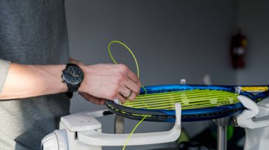 Elektronik telli makinede tenis raketinin yakın çekimi. Oyundan önce sentetik bağırsak teli değiştirme işlemi. Gazetecinin elleri.