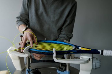 Elektronik telli makinede tenis raketinin yakın çekimi. Oyundan önce sentetik bağırsak teli değiştirme işlemi. Gazetecinin elleri.
