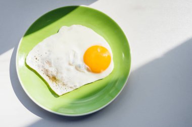 Yeni pişmiş sıcak bir yumurta yeşil bir tabakta oturur. Sağlıklı kahvaltı. Yakın plan. Yukarıdan görüntüle.