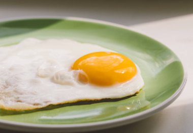 Yeni pişmiş sıcak bir yumurta yeşil bir tabakta oturur. Sağlıklı kahvaltı. Yakın plan..