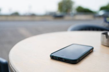 Masadaki cep telefonunun yakın plan görüntüsü. Kafe Terası.