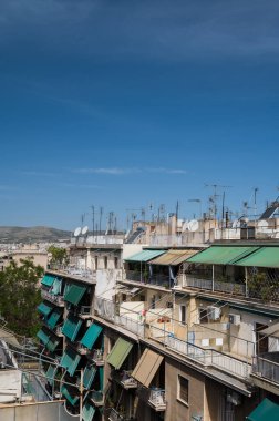 Atina, Yunanistan şehir manzarası. Tipik şehir mimarisi. Canlı binaların dışı. Teraslarda güneş panjurları. Güneşli bir yaz günü. Yeşil ağaçlar. Çatı destekli antenler.